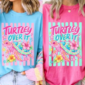 May include: Two long-sleeved shirts, one light blue and one pink, each featuring a graphic of a pink sea turtle with a floral design and the text "TURTLEY OVER IT". The shirts have a relaxed fit and are suitable for casual wear.
