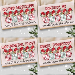 Puede incluir: Cuatro cuadrados de tela beige con diseños navideños. Cada uno presenta el nombre de una ciudad, una serie de números y la frase "small town christmas". Los diseños incluyen lazos rojos y adornos a cuadros.