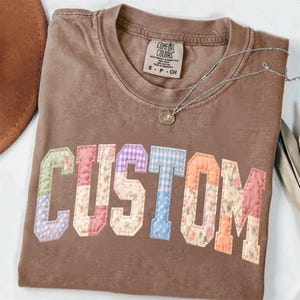 Può includere: Un cartello in legno fatto a mano con la scritta "Welcome" in un carattere giocoso. Il cartello presenta uno sfondo bianco invecchiato e una cornice marrone scuro, perfetto per una porta d'ingresso o un ingresso.