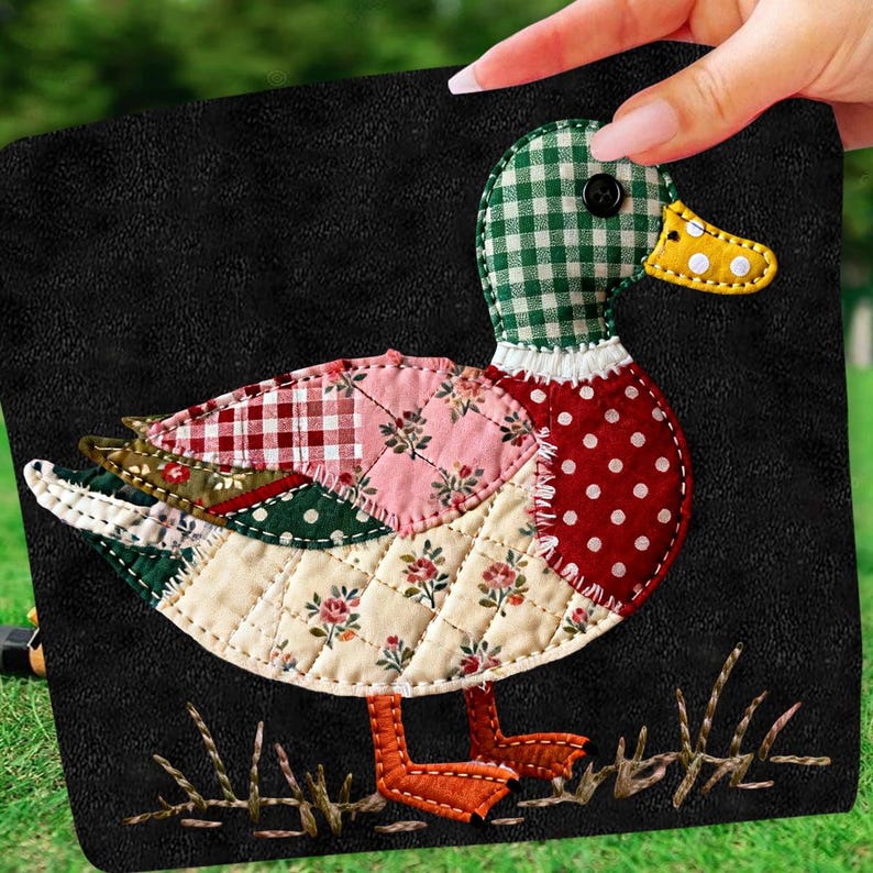 May include: A decorative duck applique with a patchwork design. The duck features a green and white checkered head, a red polka-dot body, and a yellow beak. The wings are made of various floral and patterned fabrics. The applique is on a black background.