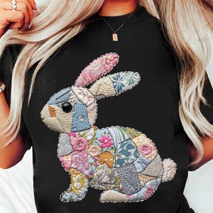 May include: Black t-shirt featuring a colourful patchwork bunny design. The bunny is made from various fabrics and colours, including pink, blue, green and yellow.