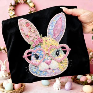 May include: Black fabric with a colorful, appliqued bunny face wearing heart-shaped glasses. The bunny's face is made of floral patterned fabric in pink, yellow, and blue. The bunny has pink ears and a pink nose. The glasses are pink.