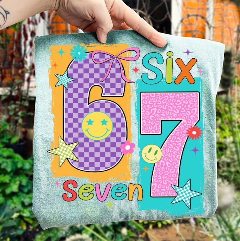 May include: A light blue, tie-dye style, decorative sign with the numbers "6" and "7" in a retro design. The number "6" is purple checkered with a yellow smiley face. The number "7" is pink leopard print. The word "Seven" is at the bottom.