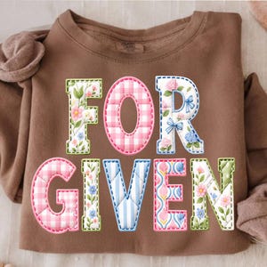 May include: A brown sweatshirt with the word "FORGIVEN" in colorful, patchwork-style letters. The letters feature floral, gingham, and striped patterns, with a stitched outline.