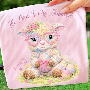 Op de afbeelding: Roze deken met een bloemmotief lammetje met een hartvormige bril en een paasei. De tekst "The Lord Is My Shepherd" en "Psalms 23:1" staan op de deken.