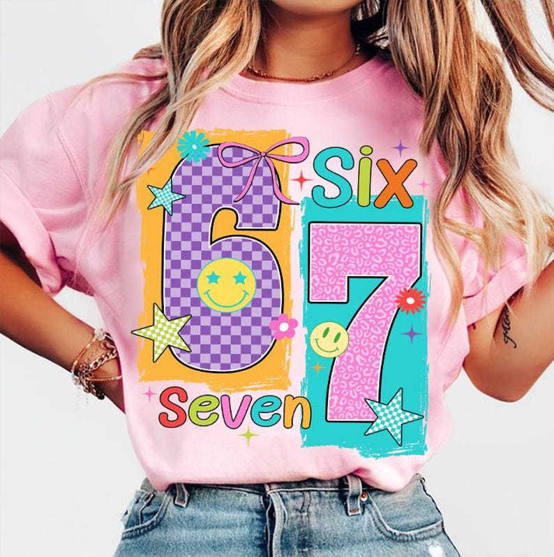 May include: Pink t-shirt with a colourful graphic design featuring the numbers "6" and "7" in a playful font. The number "6" has a checkered pattern, and the number "7" has a leopard print. The words "Six" and "Seven" are also included.
