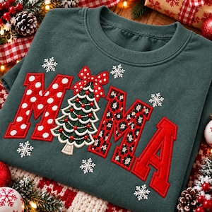 Puede incluir: Una sudadera de cuello redondo verde oscuro con la palabra MAMA en letras grandes aplicadas. La primera M es roja con lunares blancos, la A es un árbol de Navidad verde con un lazo rojo y la MA es roja con estampado de leopardo negro.