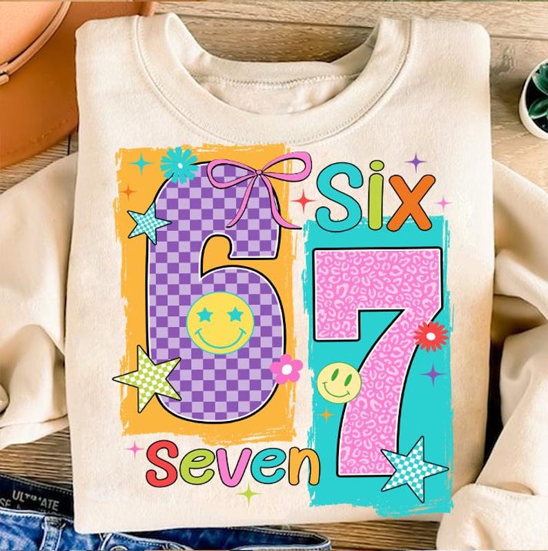 May include: Cream-coloured sweatshirt with a colourful graphic design featuring the numbers "6" and "7" in a retro style. The number "6" is purple checkered, and the number "7" is pink leopard print. The words "Six" and "Seven" are also included.