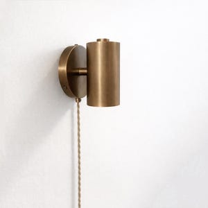 May include: A white ceramic mug with a black handle and the text "But First, Coffee" in a bold, black font. The mug is set against a blurred background, suggesting a cosy setting.