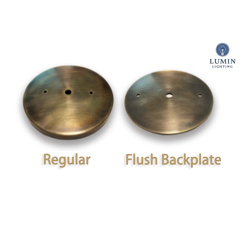 Może przedstawiać: Dwie tylne płyty do lamp sufitowych w kolorze antycznego mosiądzu. Jedna jest oznaczona jako "Regular", a druga jako "Flush Backplate". Logo "Lumin Lighting" znajduje się w prawym g&oacute;rnym rogu. Obie płyty są okrągłe z centralnym otworem i mniejszymi otworami.