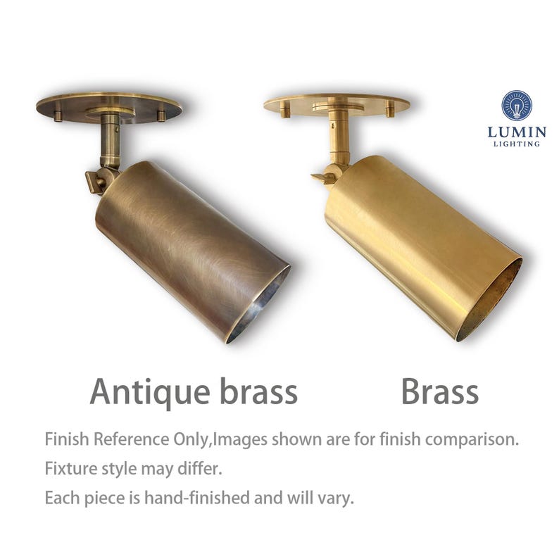 May include: Two brass-colored ceiling spotlights. One is antique brass, the other is brass. The spotlights have a cylindrical shape and are mounted on a round base. The text "Antique brass" and "Brass" are below the spotlights.