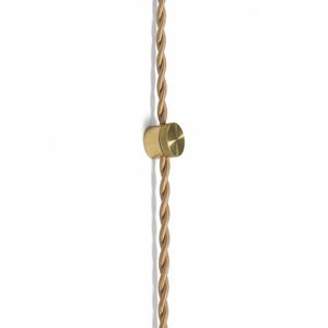 May include: A close-up of a gold-colored electrical cord with a matching cylindrical connector. The cord is twisted, and the connector is a solid, circular piece with a textured surface. The background is plain white.