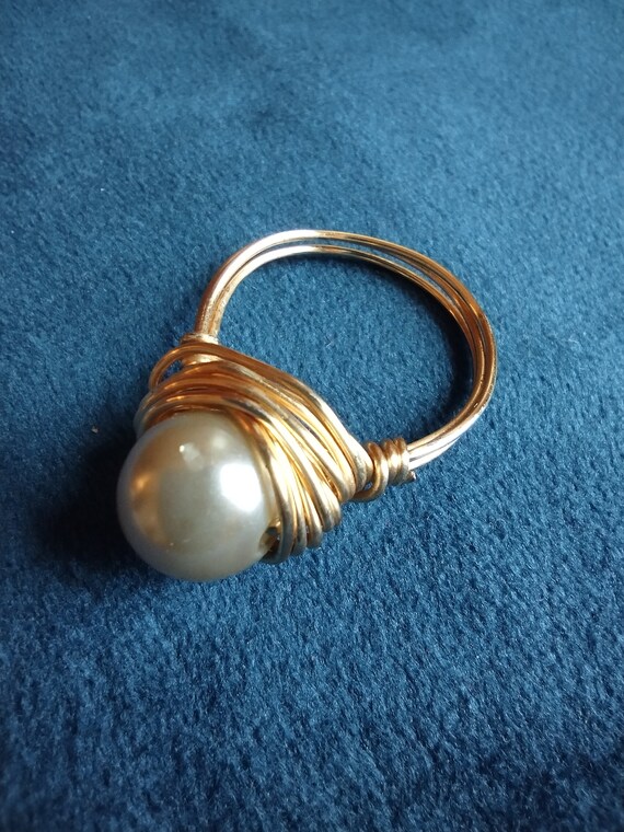 Solitary pearl ring sitting in a gold wire nest