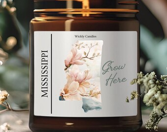 May include: A brown glass candle jar with a white label. The label features a watercolor illustration of the state of Mississippi with magnolia flowers and the text "Grow Here". The label also includes the text "Wickly Candles" and "MISSISSIPPI".