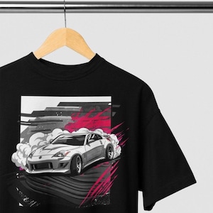 May include: Black t-shirt with a graphic of a silver sports car drifting on a gray and pink background.