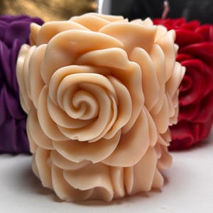 May include: A pale peach-coloured candle shaped like a rose. The candle has many layers of petals, creating a realistic rose shape.