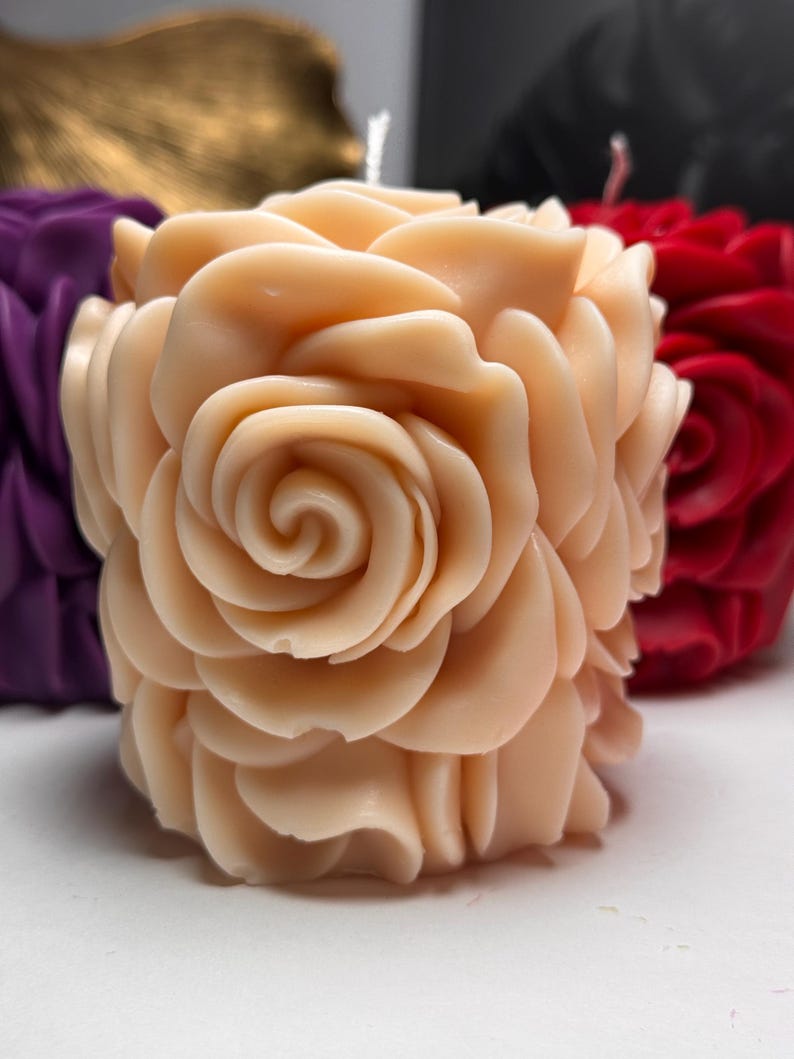 May include: A pale peach-coloured candle shaped like a rose. The candle has many layers of petals, creating a realistic rose shape.