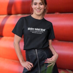 Op de afbeelding: Een zwart T-shirt met witte tekst die "pizdec nahui blyat' (rus) beschrijving van een situatie die heel erg misging." zegt.