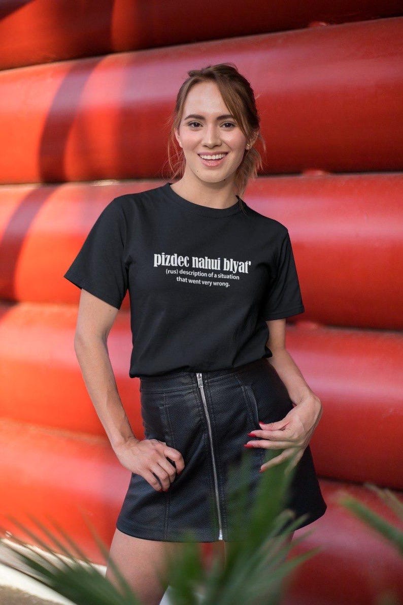 Op de afbeelding: Een zwart T-shirt met witte tekst die "pizdec nahui blyat' (rus) beschrijving van een situatie die heel erg misging." zegt.