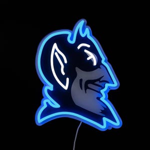May include: A neon sign shaped like a devil's head, with a blue outline and white detailing. The sign is set against a black backdrop and has a power cable.