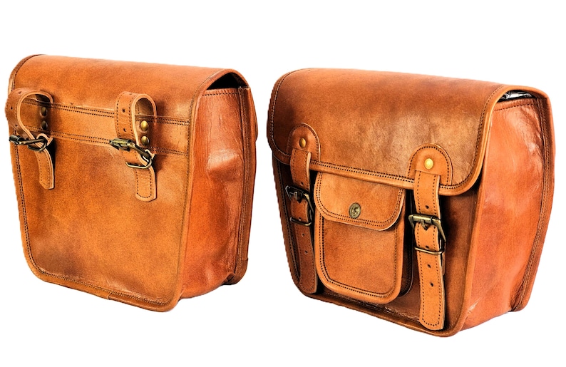 May include: Two brown leather saddlebags with buckles and straps. The bags have a flap closure and a small pocket on the front.