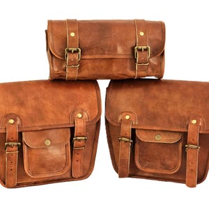 May include: Three brown leather bags with brass buckles. The top bag is a smaller, rectangular shape. The two bottom bags are larger and have a flap with a pocket.