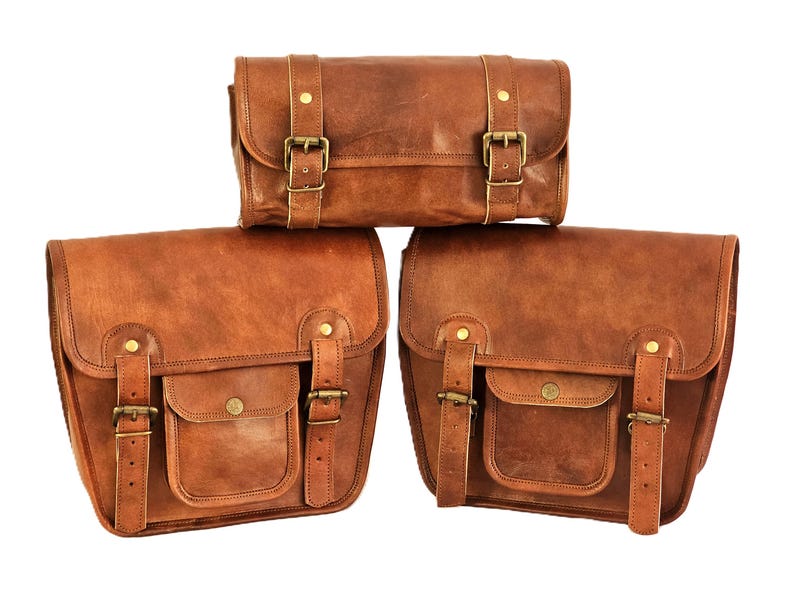May include: Three brown leather bags with brass buckles. The top bag is a smaller, rectangular shape. The two bottom bags are larger and have a flap with a pocket.