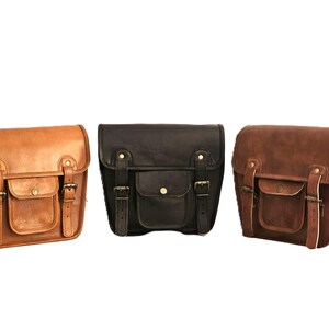 May include: Three leather motorcycle saddlebags in brown, black, and dark brown. Each bag has a flap with a buckle closure and a front pocket.
