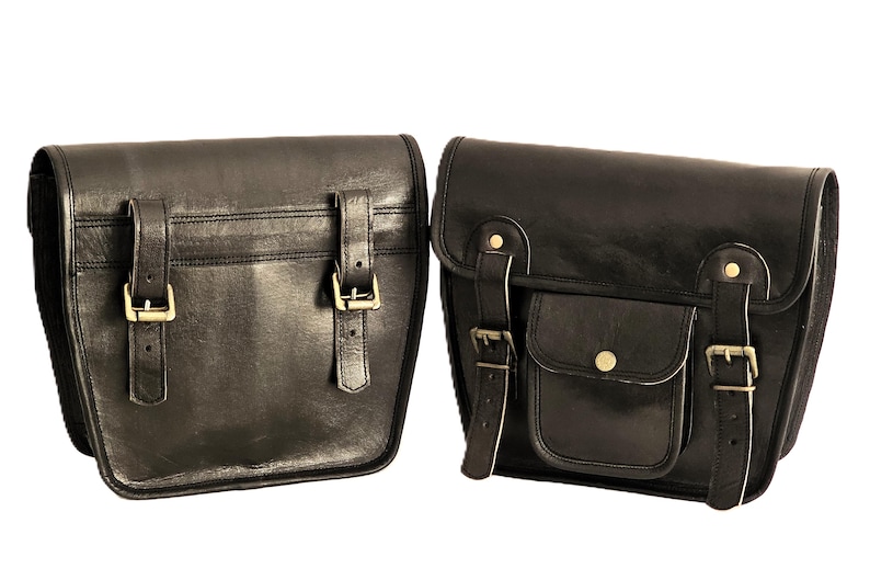 May include: Two black leather motorcycle saddlebags with buckles and straps. The saddlebags have a flap closure and a small pocket on the front.