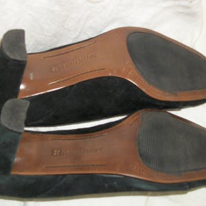 Peut inclure: Une paire de chaussures en daim noir avec des semelles en cuir brun. Les chaussures portent le nom de la marque "Naturalizer" imprim&eacute; sur les semelles.