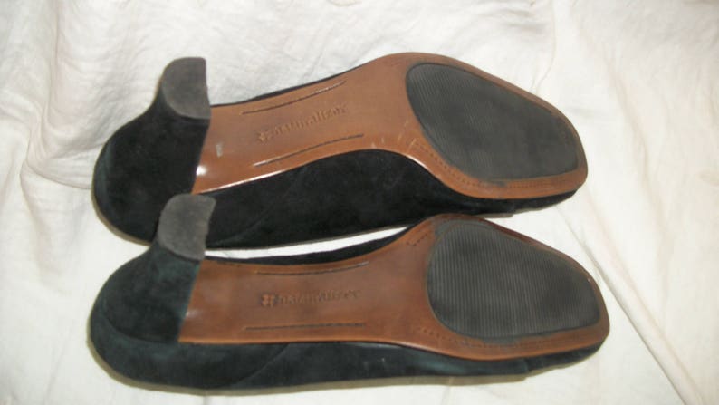 Peut inclure: Une paire de chaussures en daim noir avec des semelles en cuir brun. Les chaussures portent le nom de la marque "Naturalizer" imprim&eacute; sur les semelles.