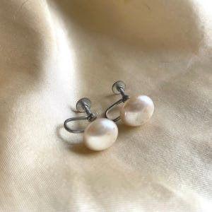 May include: A pair of silver clip-on earrings with white pearl accents.