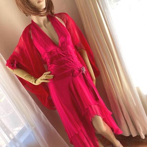 May include: A bright pink halter dress with a flowing chiffon skirt and a matching shawl. The dress has a deep V-neckline and a fitted bodice.