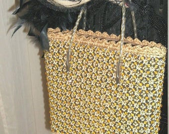 May include: A gold and black beaded handbag with clear plastic handles. The bag has a crocheted trim around the top.