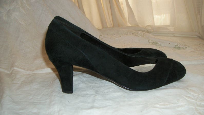 Peut inclure: Une paire de talons noirs en daim &agrave; bout ouvert avec un talon bas.