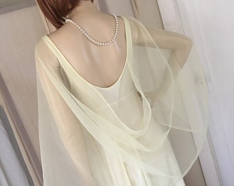May include: A pale yellow chiffon gown with a low back and a matching sheer shawl. The gown is on a mannequin with a pearl necklace.