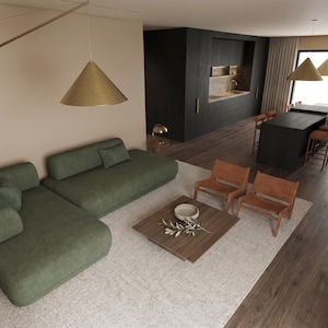 Pode incluir: Um espaço de estar em plano aberto com um grande sofá seccional verde-sálvia, duas cadeiras de couro castanho e uma mesa de centro quadrada de madeira com uma taça decorativa e um ramo. Uma ilha de cozinha preta com bancos ao fundo.