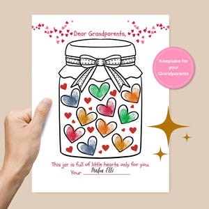 Peut inclure: Une carte blanche avec une illustration de bocal rempli de cœurs colorés. Le texte "Dear Grandparents" est en haut, avec "This jar is full of little hearts only for you" et un espace pour un nom en bas. Un cercle rose indique "Keepsake for your Grandparents."