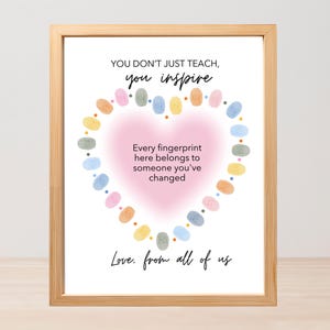 Può includere: Una stampa incorniciata con una cornice in legno chiaro. La stampa presenta il testo "YOU DON'T JUST TEACH, you inspire" sopra una forma di cuore fatta di impronte digitali colorate. Il testo "Every fingerprint here belongs to someone you've changed" è all'interno del cuore.