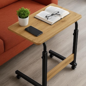 以下が含まれることがあります： 明るい木目調の表面を持つ、キャスター付きのサイドテーブル。 テーブルは黒い金属フレームで、本、メガネ、スマートフォン、小さな鉢植えの植物を置いています。 テーブルはオレンジ色のソファの隣にあります。