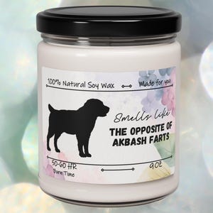 Puede incluir: Un tarro de vela blanco con tapa negra. La etiqueta dice "100% Natural Soy Wax", "Made for you", "Smells like THE OPPOSITE OF AKBASH FARTS", "50-60 HR Burn Time", y "9 oz".
