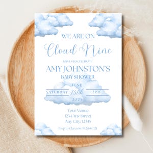 May include: A baby shower invitation with a cloud theme. The invitation reads "We are on Cloud Nine" and includes details for Amy Johnston's baby shower on June 15th, 2025, at 2 PM. The design features watercolor blue clouds.