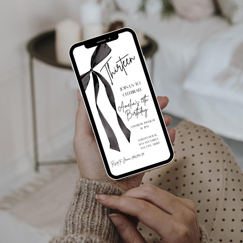 May include: A smartphone displays a black and white invitation for Amelia's 13th birthday. The design features the word "Thirteen" in elegant script, a bow graphic, and event details. The phone is held in a person's hands.