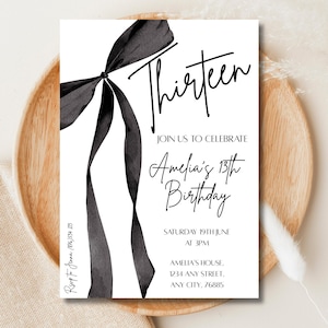 May include: A white invitation card with a black ribbon design and the word "Thirteen" in cursive. The invitation reads "Join us to celebrate Amelia's 13th Birthday" with event details. The card is on a wooden plate.