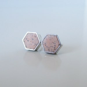 Puede incluir: Un par de pendientes de botón hexagonales de plata con un diseño moteado rosa y blanco.