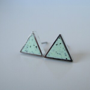 Puede incluir: Un par de pendientes triangulares plateados con un diseño verde claro moteado.