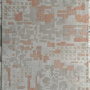 May include: A rectangular rug with a geometric pattern. The rug features a light gray background with a repeating pattern of small white and orange cross-stitch-like shapes. The border is a solid light orange color.