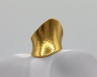 Puede incluir: Un anillo de oro martillado con una banda ancha y un diseño curvo.