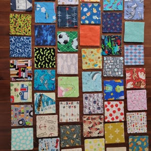 May include: A selection of small, square fabric patches featuring diverse patterns and colours. Designs include geometric shapes, animals, and objects like cars and anchors. The patches are arranged on a wooden surface.