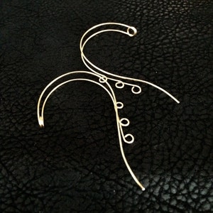 May include: Gold wire ear cuff with multiple loops and a curved design.